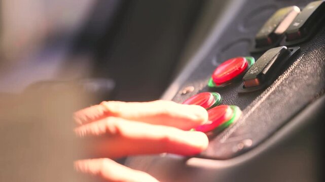 Bus driver hand presses red button to open passenger doors in sunlight