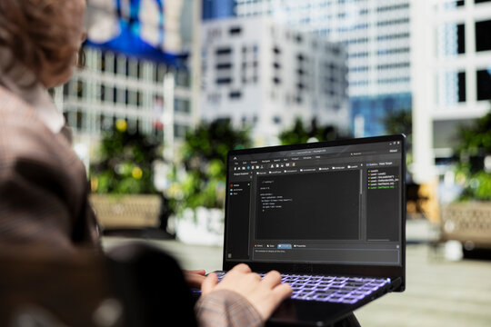 Close up of engineer on park bench writing code on laptop
