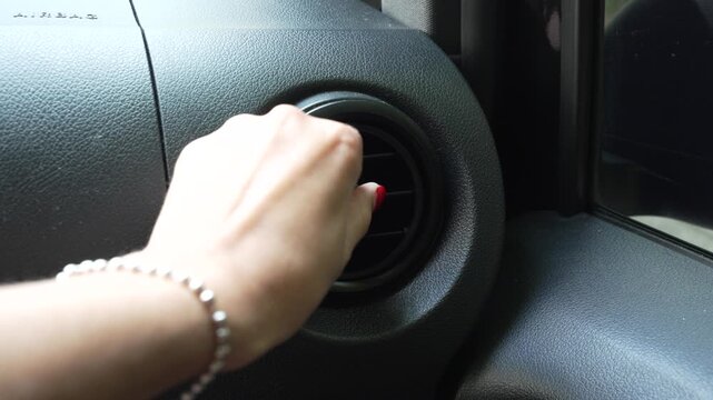 Close-up horizontal video of a female hand rotating the air conditioning vent in a modern car to adjust airflow direction and cabin comfort