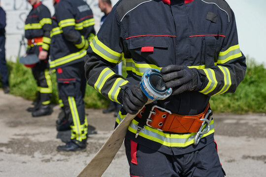 Firefighter Preparing Hose Wearing Protective Uniform And Safety Belt During Training Drill