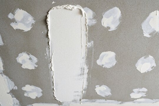 Smooth plaster ceiling being installed with white compound on gray drywall panels. Some spots are taped and mudded, indicating unfinished work in residential construction.
