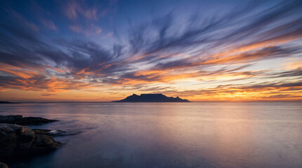 Fototapeta premium Table Mountain silhouette at sunset over the calm ocean