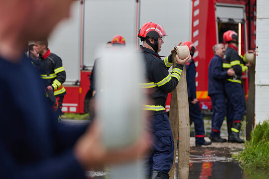 Firefighters Unrolling Hose Near Red Fire Truck During Emergency Response Training