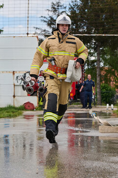 Firefighter Running With Hose And Manifold During Emergency Response Training Near Fire Truck