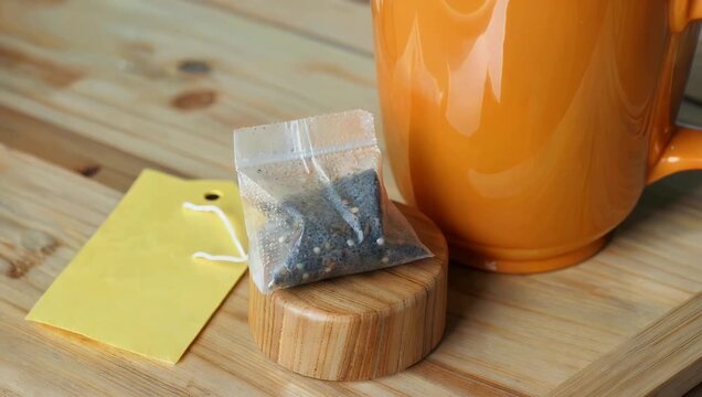 Clean 4K product mockup composition featuring a single tea bag sitting on a wooden stand with a blank tag set against orange tea cups tailored for hot beverage branding and packaging design