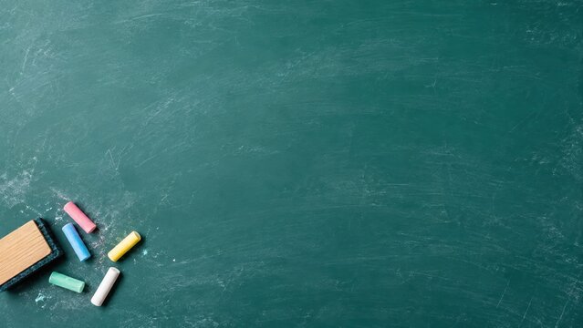 green school chalkboard with colorful chalk sticks and eraser in bottom corner with large copy space