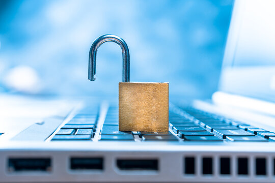 An unlocked lock is lying on the laptop keyboard.