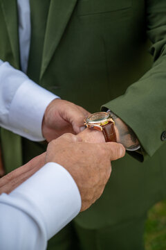 Groom in green suit adjusting wrist watch and sleeve cuff close up before wedding ceremony