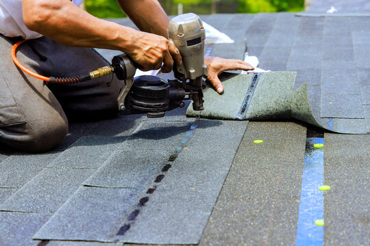 Roofing work in progress on house with shingles being installed