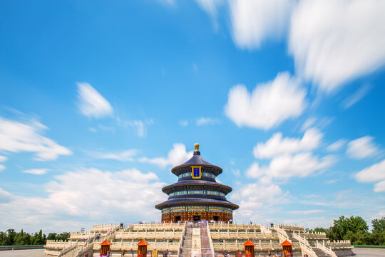 A three-tiered circular imperial religious building stands on white stone terraces under a bright blue sky with white clouds.