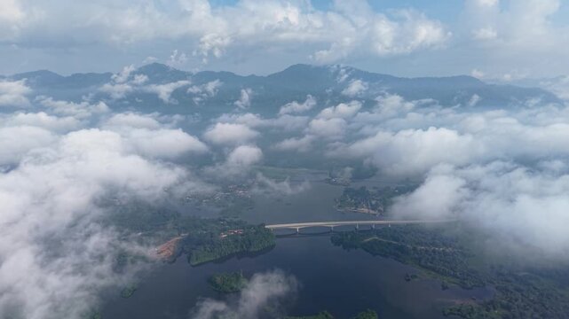 A peaceful aerial view showing a river winding through forested land beneath a partly cloudy sky with distant mountains at Tasik Raban