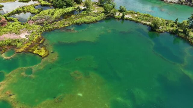 Aerial view shows serene turquoise waters. Lush greenery surrounds calm, shallow pools
