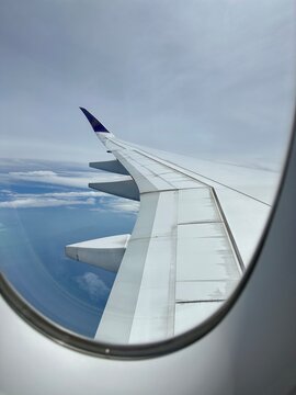 Airplane wing viewed through a window above the clouds