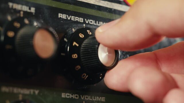 Close-up of plugging a jack into a bass guitar amplifier and turning up the volume knob, live concert show, playing music on guitar tube amplifier.