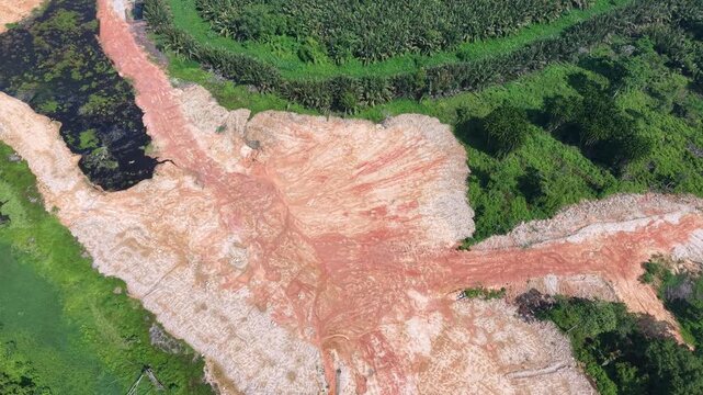 Aerial view of red sludge spreading across green jungle.