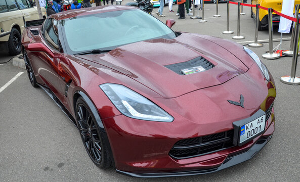 Deep metallic red Chevrolet Corvette C7 Stingray boasts sharp, aggressive body lines and vented hood, representing modern American muscle and sports car excellence