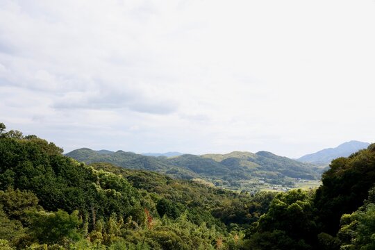 日本の田舎風景。緑の山間に点在する家々と薄曇りの空