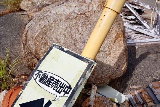 不動産売出中の看板。物が散乱した乱雑な土地の一角