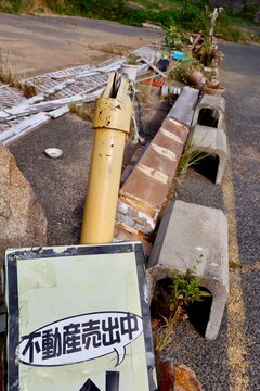 不動産売出中の看板。物が散乱した乱雑な土地の一角