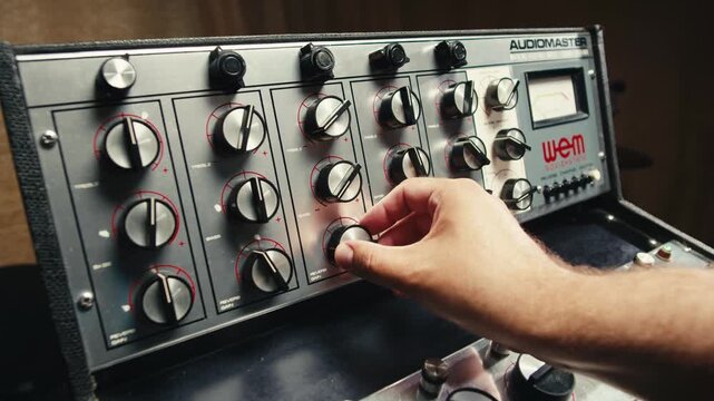 Music studio close up, Close up hands shot of sound engineer using mixing console, remote control for adjusting sound, audio mixer. Musician creates music, makes remix for DJ set. Sound recording