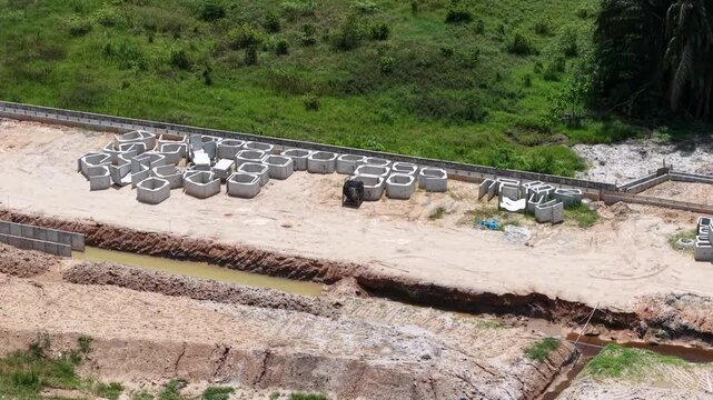 A construction site featuring a series of concrete pipes laid out on dirt and prepared for installation