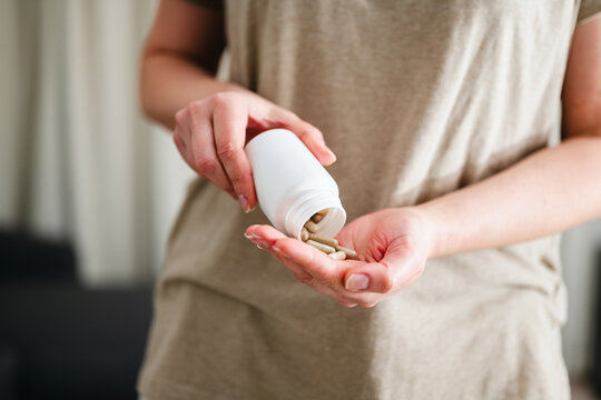 Woman pouring a pile of pills, capsules from a bottle in hand. Prescription medication, treatment sickness concept