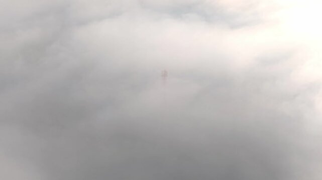 Ground level view of a telecom tower barely visible through dense mist, atmospheric minimalist landscape.