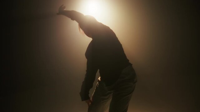 Dancer woman is dancing hip hop contemporary in dace hall close-up on white light. Shooting of modern slow dance choreography. Motion of female dancer expressing feelings in dance movings. 