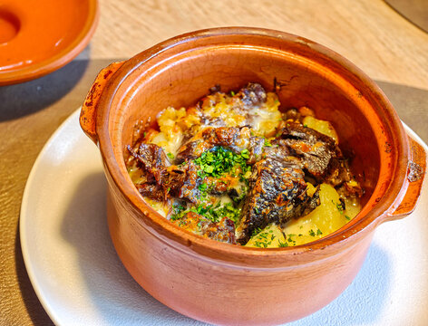 Hearty home-cooked dish &mdash; a stew with meat and potatoes, baked in a clay pot and sprinkled with fresh herbs.