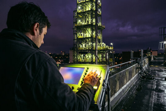 Night shift technician operating industrial control panel