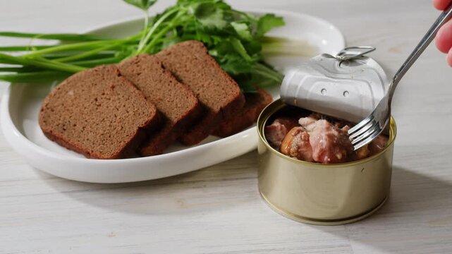 Cod liver superfood can, omega 3 Smoked cod liver in oil in open tin can with fresh greens on wooden table. Seafoods delicacy