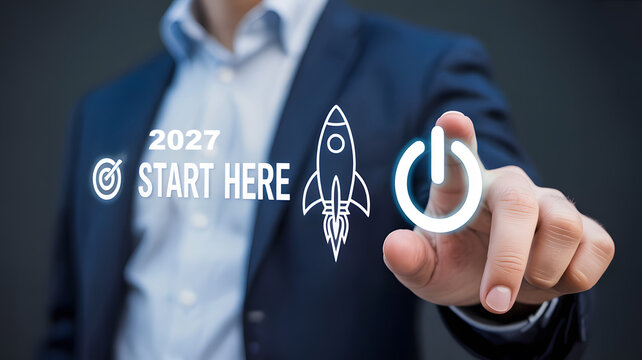 Business growth and future planning concept photo. Businessman in a navy suit pushing a glowing power button interface. Featuring white rocket ship, target icon, and startup text for annual corporate 
