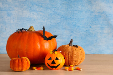Naklejka premium Halloween celebration and autumn holidays, pumpkins with candy corn and spooky decorations on a wooden table against a blue textured background