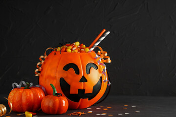 Naklejka premium Halloween celebration and trick or treat tradition, jack o lantern candy bucket with sweets and festive decorations on a dark textured background
