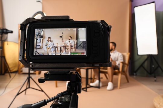 Video production and content creation, professional film crew recording an interview with two people in a studio setting