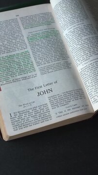 Opening to the book of 1 John, of the New Testament in the Holy Bible. New Revised Standard Version. Vertical video.
