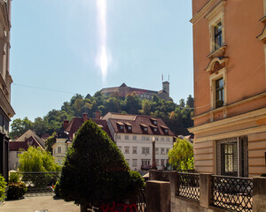 Ljubljana Castle stands prominently atop a hill overlooking the traditional architecture of Ljubljana, Slovenia, on a bright and sunny day, highlighting the city's historic and scenic landscape. © Marcos