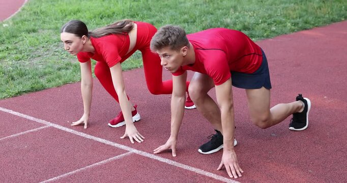 Athletes getting into start position and running at stadium