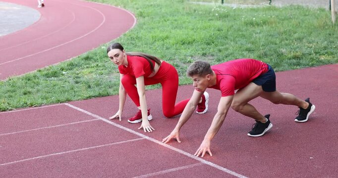 Athletes getting into start position and running at stadium