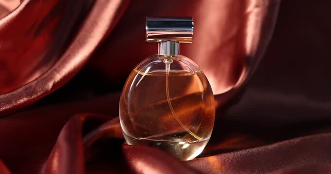 Bottle of aromatic perfume on brown silk, closeup
