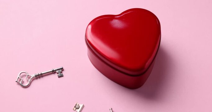 Choice concept. Heart shaped box and different keys on pink background, closeup. Camera moving