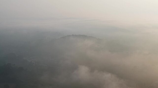 Early morning mist and dense fog envelop a mountainous forest landscape at Tasik Raban