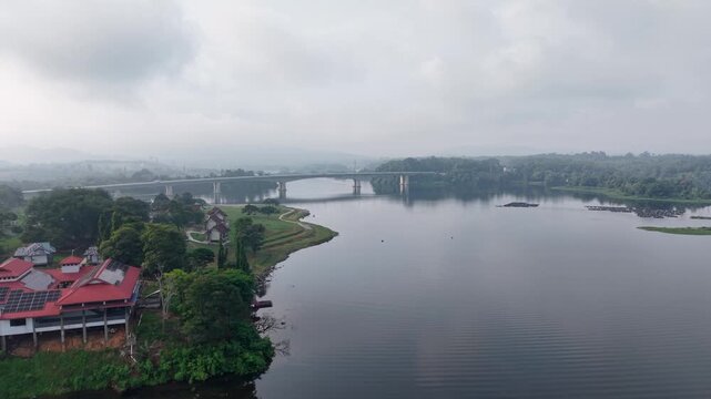 Aerial view captures a wide river under cloudy skies. Reflective water mirrors distant hills at Tasik Raban