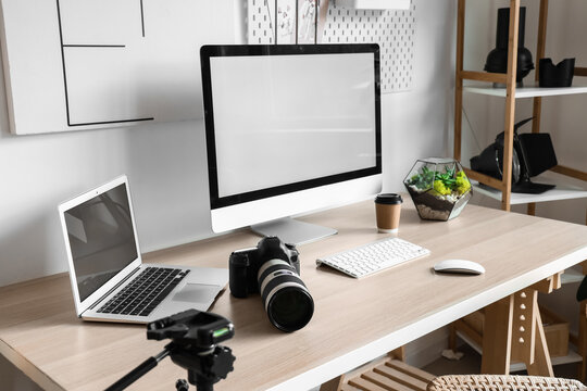Photographers workplace with computer monitor and laptop in light office