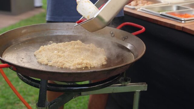 Chef adding tomato sofrito to paella pan