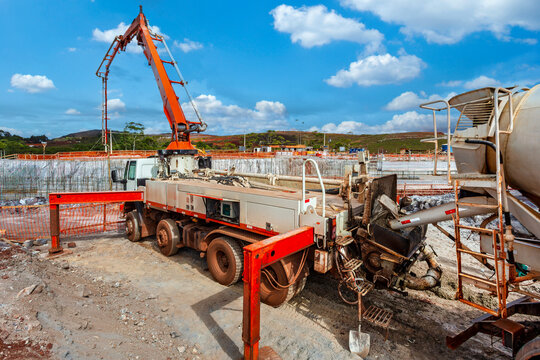 Heavy duty concrete pump truck pouring liquid concrete into the foundation at a large outdoor construction site.