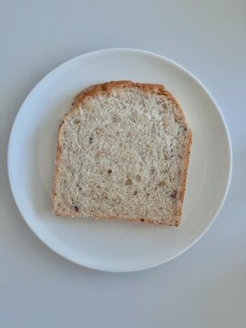 Single slice of multigrain bread on a white plate with copy space