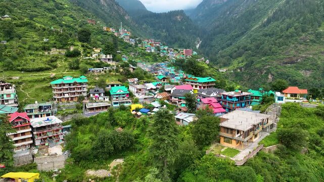 Awe-inspiring aerial pullback revealing the vast, sunlit wilderness surrounding traditional Himalayan architecture in northern India.