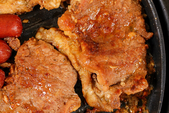 Barbecue featuring fatty, succulent cuts prepared on an electric grill, boasting a tender texture and caramelized fat.