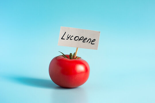 A bright red tomato, close‑up, against a light background, with the word &ldquo;lycopene&rdquo; written on the paper label, also close‑up.